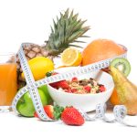 Diet weight loss breakfast concept with tape measure organic green apple, cereal bowl, orange juice, pineapple, muesli cereal bowl, pear, kiwi, lemon, strawberries on a white background